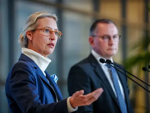 Zwei Personen sprechen in Mikrofone bei einem Event.