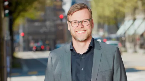 Ein blonder junger Mann mit Brille und Dreitagebart