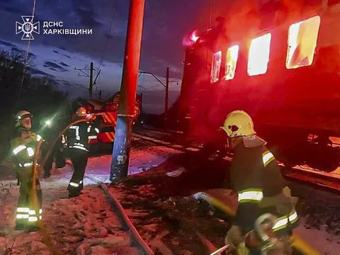 Feuerwehrleute bei einem brennenden Zug bei Nacht.