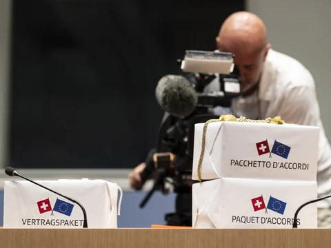 Mann hinter Kamera bei Paketen mit Flaggen der Schweiz und EU.