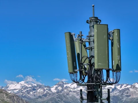 Mobilfunkmast vor verschneiten Bergen.