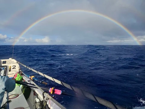 Boot auf dem Ozean mit Regenbogen im Himmel.