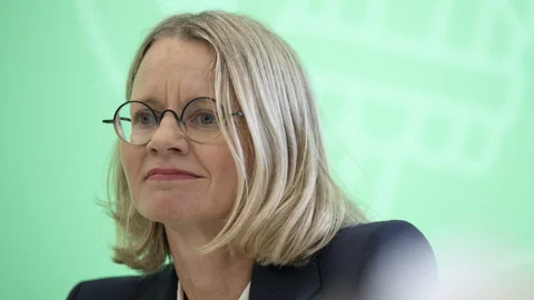 Frau mit Brille vor grünem Hintergrund.