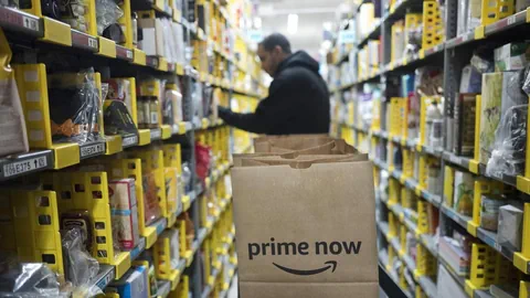 Ein Amazon Lagerarbeiter steht vor gefüllten Regalen