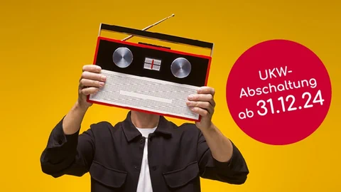 Ein Mann hält sich ein Radiogerät vor den Kopf.