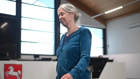 Frau in blauem Hoodie steht in einem modernen Raum.