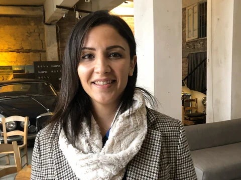 Frau in einem Raum mit Vintage-Autos im Hintergrund.