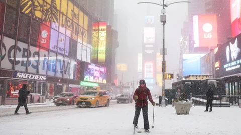 Person mit Skiern in verschneitem, buntem Stadtzentrum.