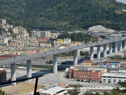 Lange Brücke über städtische Gebäude und Hügel im Hintergrund.