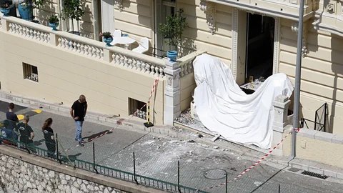 Drei Personen stehen vor einem Gebäude mit weissem Laken und Absperrband.