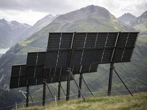 Solarpaneele auf einer Bergwiese mit Bergblick.