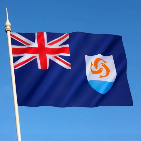 Eine Flagge mit britischem Logo oben links und unten rechts ein Wappen mit drei Fischen über einem hellblauen Boden.