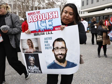 Person hält Plakat mit Text 'Nurses Say Abolish I.C.E.' und Bildern von drei Personen bei Demonstration.