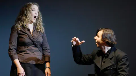 Der sitzende Teodor Currentzis dirigiert eine stehende Sängerin.