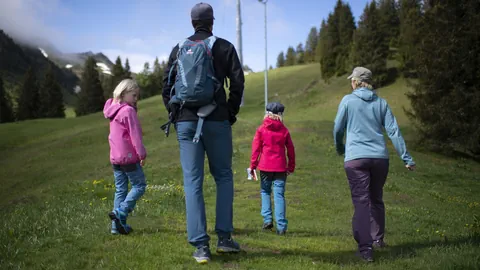 Familie mit zwei Kindern läuft über eine Wiese.