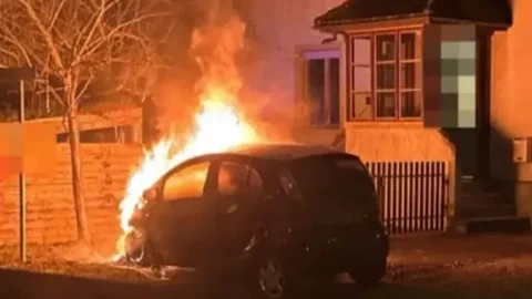Auto brennt vor einem Haus.