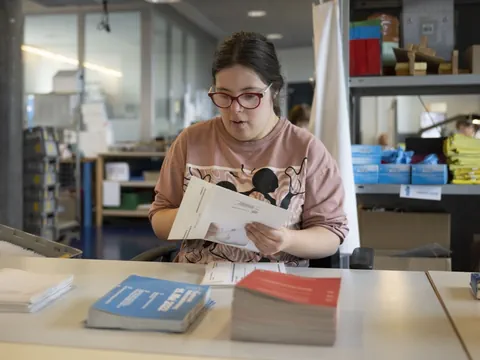 Person sortiert Papier an einem Tisch in einem Büro.