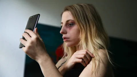 Frau betrachtet ein Smartphone mit nachdenklichem Ausdruck.