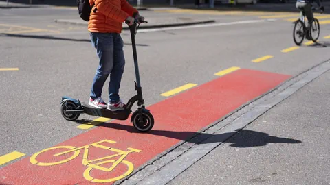 Jemand fährt mit E-Trottinett auf den Velostreifen.