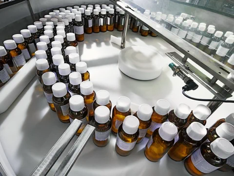 Flaschen mit weissen Kappen auf einem Förderband in einer Fabrik.