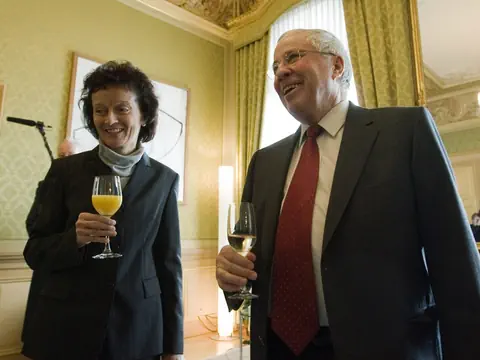 Zwei Personen in formeller Kleidung halten Gläser in einem eleganten Raum.