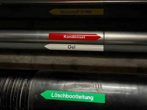 Rohre sind angeschrieben mit den Stoffen, die sie transportieren.