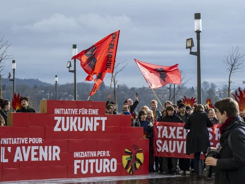 Menschen versammeln sich mit roten Fahnen und Bannern bei einer Demonstration.
