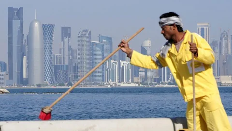 Ein Mann wischt vor der Skyline von Doha.