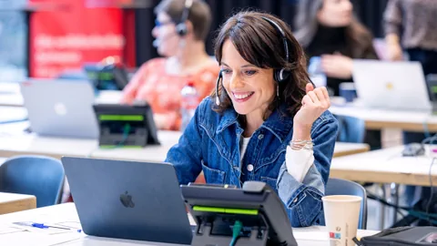 Frau lächelt und arbeitet am Laptop im Büro.