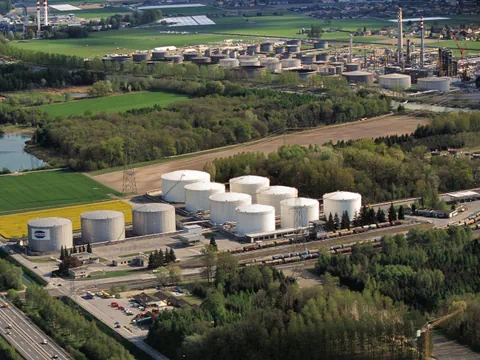 Luftaufnahme von Raffinerie und Tanks in grüner Landschaft.