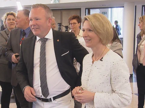 Gruppe von Menschen bei Veranstaltung, zwei Personen im Vordergrund lächelnd.