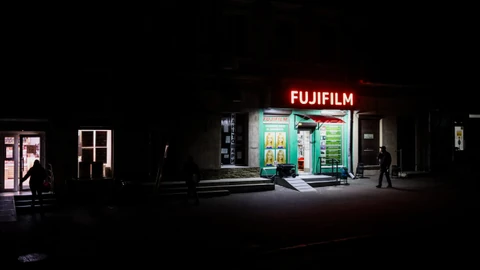 Beleuchtetes Fujifilm-Geschäft bei Nacht.