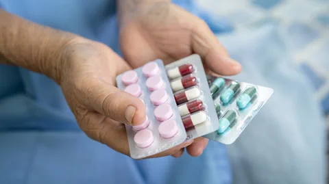 Nahaufnahme einer Hand, die Tabletten in Blisterpackungen hält.