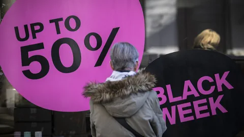 Frau von hinten schaut auf Schaufenster, an dem «Black Week» und «Up to 50 %» hängen.