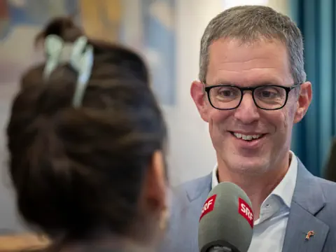 Mann im Anzug bei Interview mit Mikrofon.