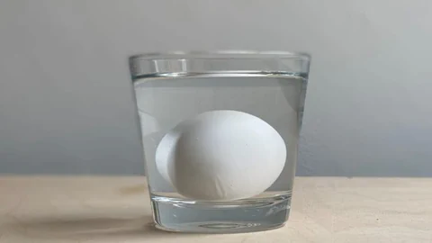 Ein Glas Wasser mit einem rohe Ei drin, um die Frische des Eis zu testen