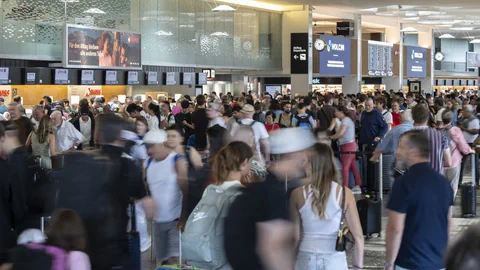 Menschenmenge in einer belebten Flughafenhalle mit Check-in-Schaltern.