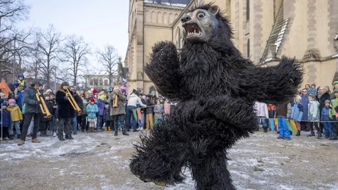 Person im Bärenkostüm tanzt bei einer Veranstaltung vor Publikum.