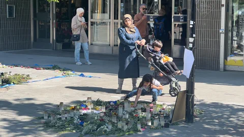 Eine Frau mit Kopftuch und ihren Kindern am Tatort in Farsta.