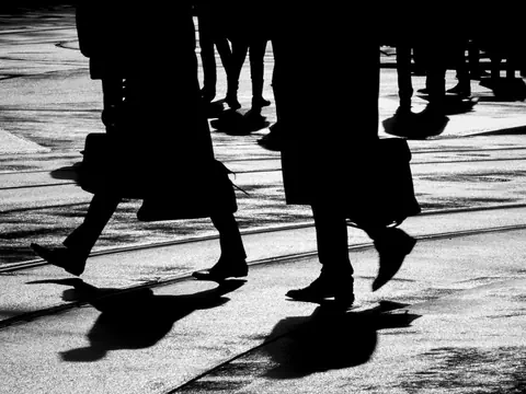 Silhouetten von Menschen, die über einen Bürgersteig gehen.
