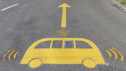 Gelbes Symbol eines Autos mit Pfeil auf Asphaltstrasse.