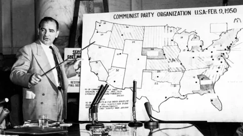 Joseph McCarthy zeigt auf einer USA-Karte so die kommunstische Partei aktiv sei