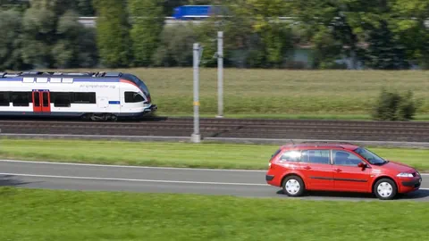 Auto auf Strasse neben Zug auf Schiene