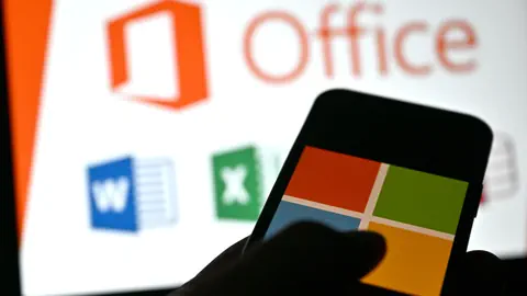 Smartphone mit Microsoft-Logo vor Office-Icons auf Bildschirm.