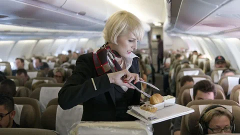 Flugbegleiterin, die Essen in einem Flugzeug serviert.