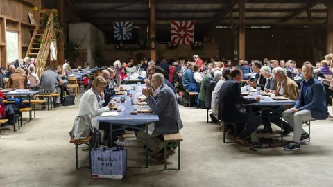 Ein Bauernfrühstück in der Schweiz. Menschen sitzen an Festbänken.