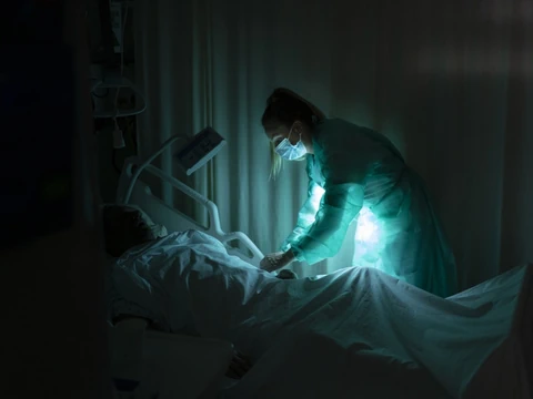 Pflegekraft im Schutzanzug behandelt Patienten im Krankenhaus.