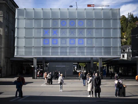 Menschen vor modernem Gebäude mit leuchtenden blauen Symbolen.