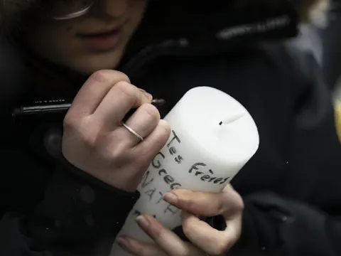 Nahaufnahme einer Person, die auf eine weisse Kerze schreibt.