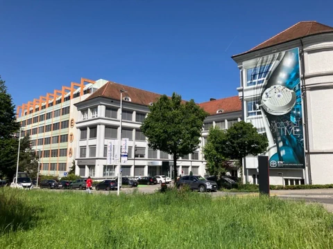 Gebäude mit Werbebanner und grüner Wiese im Vordergrund.